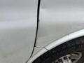 Close-up of the side of a 2014 GMC Savana showing a dent and scratches on the silver paint with part of the tire visible