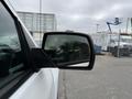 A side mirror of a 2016 GMC Sierra 1500 reflecting the surroundings with a cloudy sky in the background