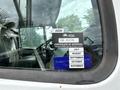 A 1998 Freightliner FL80 truck with a visible certificate of approval sticker on the windshield and various month labels including July August September October November