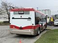 A 2016 Grande West Vicinity bus with a red and white design is parked, showing its rear and side features, including the license plate number 2038