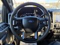 Steering wheel of a 2020 Ford F-350 with controls for audio and cruise settings visible. Ford logo in the center and digital display in the background.