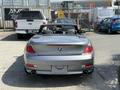 A silver 2004 BMW 6-Series convertible with the top down parked with its rear facing the viewer showcasing twin exhausts and distinctive taillights