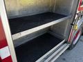 Interior of a 2006 Emergency One Fire Truck showing two empty metal storage shelves with black rubber mats