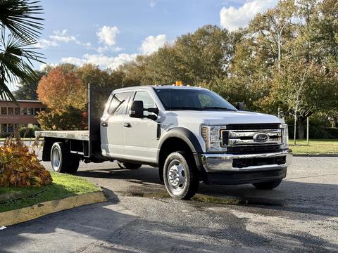 A 2019 Ford F-550 truck with a flatbed design featuring a chrome grille and a cab with a light bar on top