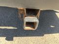 A close-up of the trailer hitch receiver attachment on a 2013 Chevrolet Silverado 1500 showing signs of rust and wear