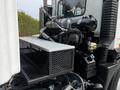 A 2012 Autocar Xpert truck showcasing the engine compartment with visible components including pipes and a mesh storage shelf attached to the side