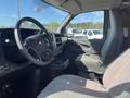 The interior of a 2013 Chevrolet Express showing the driver's seat dashboard steering wheel and center console with cup holders