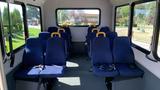 Interior of a 2011 Chevrolet Express showing rows of blue seats equipped with yellow seatbelts