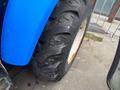 A blue New Holland T475 tractor tire showing deep treads and sidewall markings