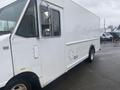 A white 2012 Ford Econoline truck with a boxy shape featuring large side mirrors and a blank side panel without any visible markings