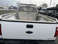 A white 2010 Ford F-250 Super Duty truck with a metal tool storage unit in the truck bed