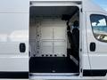 A 2021 RAM Promaster van with an open side door revealing the interior space featuring two front seats and a bare metal cargo area