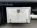 An aluminum storage box attached to the side of a 2006 Freightliner M2 112 truck with a latch and handle