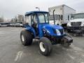 A blue 2007 New Holland TN70A tractor with large tires and a protective cab structure standing in a parking area