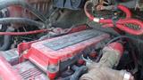 A dirty red Cummins engine with visible wiring and hoses in a Freightliner M2 106 chassis