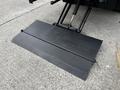 A metal loading ramp with a diamond plate surface is lowered from the back of a Hino 268 truck