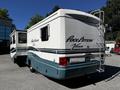 A 2000 Ford Motorhome, white with teal accents, featuring the name "Pace Arrow Vision" on the side and a ladder attached to the rear.