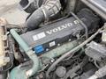 Close-up of a 2012 Volvo VNL engine showing various components including a black engine cover with the Volvo logo and colorful hoses مهڻ