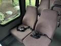 A pair of brown fabric seats with seatbelts inside a vehicle