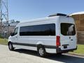 A 2023 Mercedes-Benz Sprinter van in white with tinted windows and a sleek design featuring a black roof element and silver wheels positioned at an angle