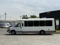 A 2017 Chevrolet Express passenger van in white with large windows and a gray base is parked sideways