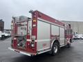 A red 2006 E-One Fire Truck featuring a metallic grille multiple compartments and a hose connection on the rear side with the number 911 displayed