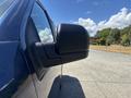 A side view of a blue 2015 Ford F-150 showing the side mirror and part of the vehicle's door