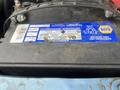 A blue 2006 Ford Econoline with its hood open revealing the vehicle's battery labeled with maintenance and warning information