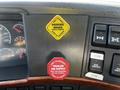 Dashboard controls of a 2005 Volvo VND 122 featuring yellow and red stickers indicating parking brake and trailer air supply functions