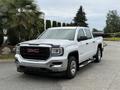 A 2016 GMC Sierra 1500 in white with a chrome grille and black accents parked on a driveway with a palm tree nearby