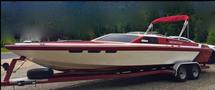 A 1989 Nordic Viking boat with a sleek design featuring a red and white color scheme, a high bow, and a red canopy, mounted on a dual-axle trailer