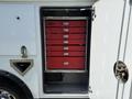 A white service truck with an open compartment featuring several red drawers stacked vertically inside