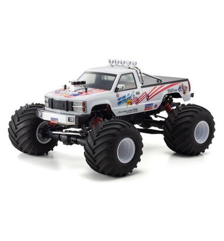 A Kyosho USA-1 VE Electric 1/8 Scale ReadySet Brushless Monster Truck with oversized tires and a colorful body design featuring racing decals and lights on the roof