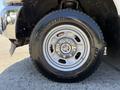 Close-up of a silver alloy wheel with a black tire featuring an aggressive tread design mounted on a 2012 Ford F-350 SD
