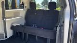 A 2016 Dodge Grand Caravan with a black fabric bench seat in the middle row showing two seat belts and ample seating space