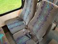 A pair of gray bus seats featuring blue and purple wave patterns and equipped with seatbelts