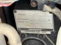 A close-up view of a nameplate showing specifications for a Yanmar engine, including model number, displacement, and engine number