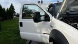 A 2007 Ford F-550 pickup truck with an open driver door and the hood raised revealing the engine compartment