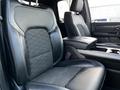 The interior of a 2019 RAM 1500 featuring black leather seats with a textured fabric center and a console between them