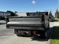 A black 2018 Ford F-550 flatbed truck viewed from the rear with a metal bed and visible taillights