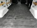 The interior cargo space of a 2023 Ford Transit with a black patterned rubber floor and no additional cargo or seating present