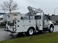 A 2013 International DuraStar truck equipped with an Altec aerial lift and a material bucket mounted on the rear