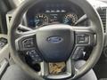 Steering wheel of a 2016 Ford F-150 featuring controls for audio and cruise settings with the Ford logo in the center