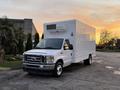 A white 2021 Ford Econoline with a boxy cargo area and a rooftop cooling unit parked on a driveway