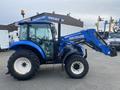 A blue 2016 New Holland T475 tractor with a front loader attachment parked on a lot showcasing its large tires and cab design