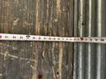 A measuring tape extended across a wooden surface with visible measurements up to 100 inches