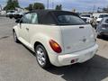 A 2005 Chrysler PT Cruiser convertible in white with a black soft top, showcasing its distinct rounded shape and rear design