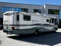 A 2000 Ford Motorhome with a white and teal exterior featuring a rear ladder and multiple windows on the side
