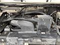A close-up view of the engine compartment of a 2012 Ford Econoline featuring various engine components and wiring with a metal casing and hoses visible