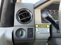 Dashboard controls of a 2008 Ford F-550 including air vent and switch for lights with a notice sticker about clutch pump inspection
